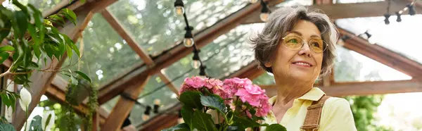 Beautiful senior woman enjoys her time in a lush garden surrounded by blooming flowers. — стоковое фото
