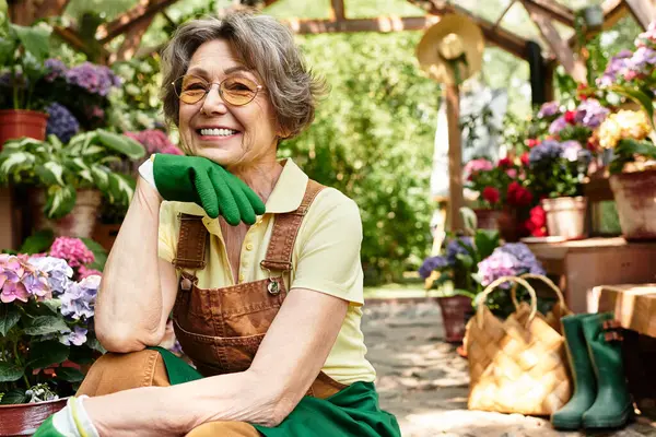 Bright atmosphere surrounds a happy senior woman relaxing among vibrant flowers while gardening. — стоковое фото