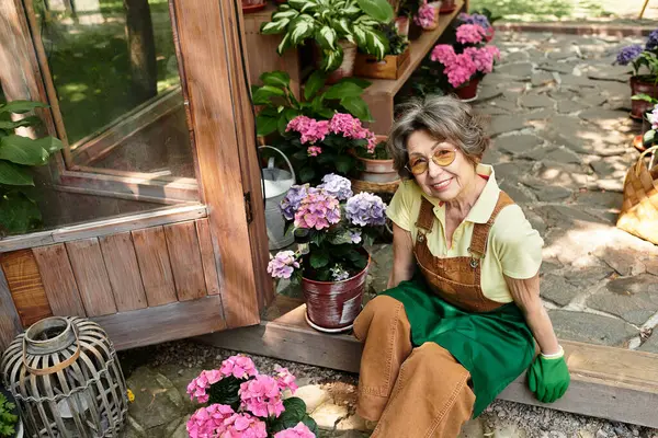 A senior woman enjoys tending to flowers in her delightful garden, radiating happiness and serenity. — Stock Photo