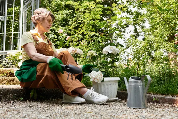 Senior woman in garden lovingly tending to white flowers while enjoying the serene atmosphere — Stock Photo