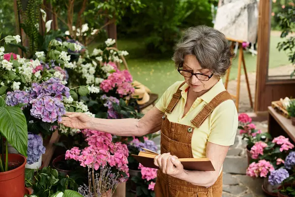 Senior woman enjoys her time in a colorful garden, surrounded by beautiful flowers and plants. — Stock Photo