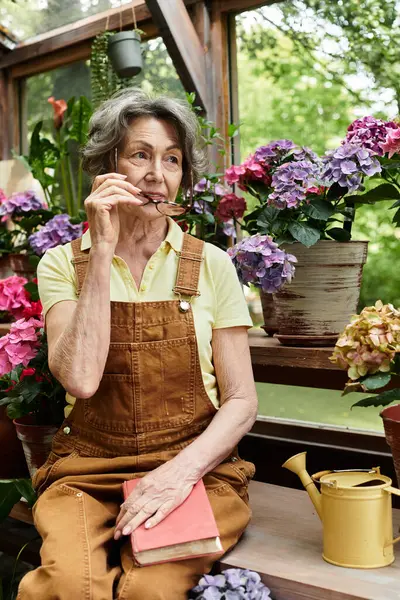 A senior woman relaxes in her garden, savoring her thoughts amidst vibrant flowers and greenery. — стокове фото