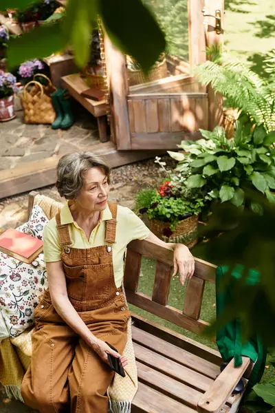 Amidst lush greenery, a senior woman relaxes on a wooden bench, appreciating natures beauty. — Stock Photo