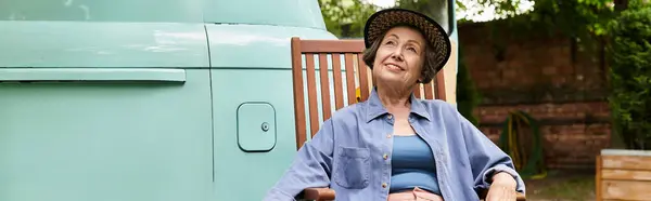 Amidst lush greenery, a joyful senior woman relaxes in her garden, soaking in the sun and serenity. — Stock Photo