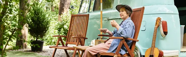 A beautiful senior woman sits peacefully in a garden, sipping tea while enjoying natures calm. — Stock Photo