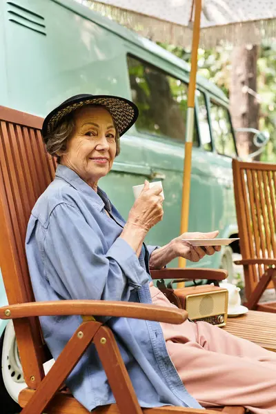 A beautiful senior woman relaxes in her garden, sipping tea and savoring the warm sunshine. — Stock Photo