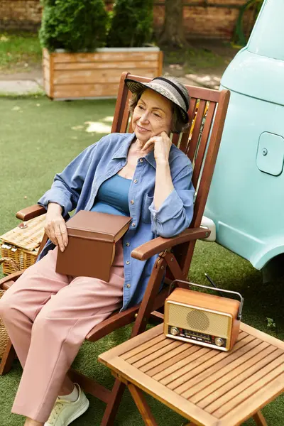 A senior woman relaxes in a garden chair, surrounded by greenery and vintage charm. — Stock Photo