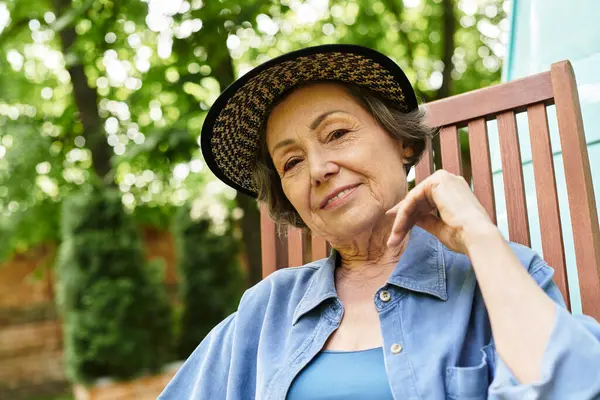 Senior woman sits comfortably in a garden chair, enjoying a peaceful moment in natures beauty. — Stock Photo