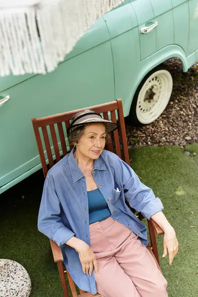 A senior woman relaxes in her garden, soaking up sunshine while seated comfortably. — Stock Photo