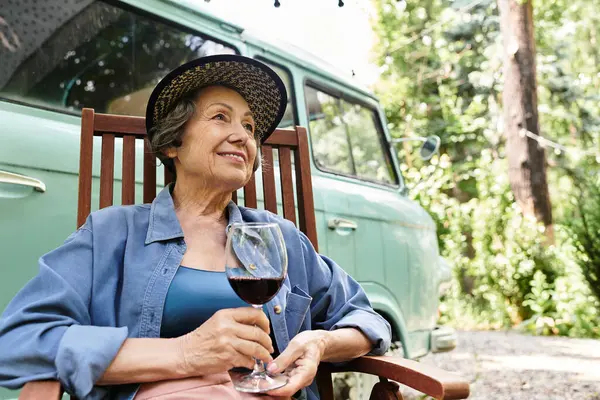 A beautiful senior woman relaxes in a garden, sipping red wine and basking in natures tranquility. — Stock Photo