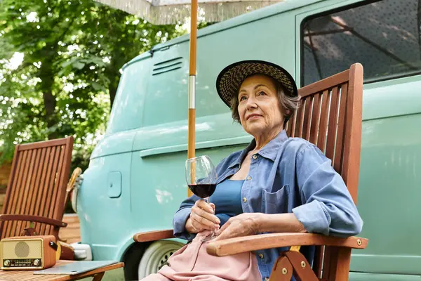 A beautiful senior woman relaxes in a lush garden, savoring her wine while basking in the warmth. — Stock Photo