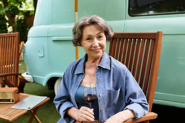 A senior woman relaxes in a garden, savoring a glass of wine and enjoying the tranquil ambiance. — Stock Photo