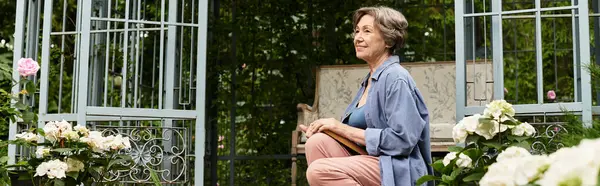 A beautiful senior woman basks in tranquility while tending to lush flowers in her garden sanctuary. — стокове фото