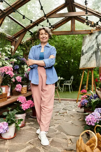 Mujer mayor abraza la belleza de su jardín, rodeado de coloridas flores y vegetación. - foto de stock