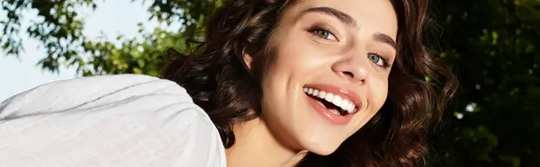 A young woman radiates joy while smiling amid lush greenery on a warm summer day, banner — Stock Photo