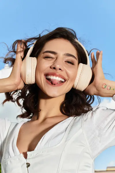 Bright summer day shines on a cheerful woman with wavy hair, lost in music outdoors. — Stock Photo
