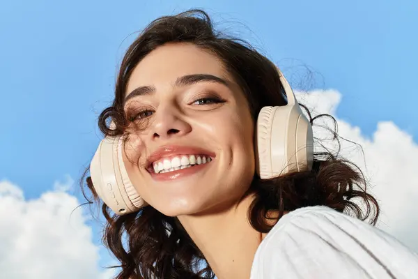 A cheerful young woman with wavy brown hair smiles while enjoying the summer outdoors. — Stock Photo