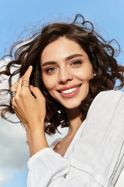 Wavy-haired young woman enjoying a sunny day outdoors, radiating joy under a clear blue sky. — Stock Photo