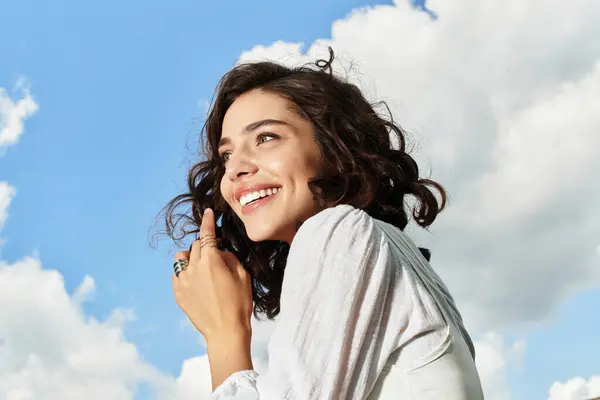 A pretty young woman enjoys a sunny summer day outdoors, smiling against a vibrant blue sky. — Stock Photo