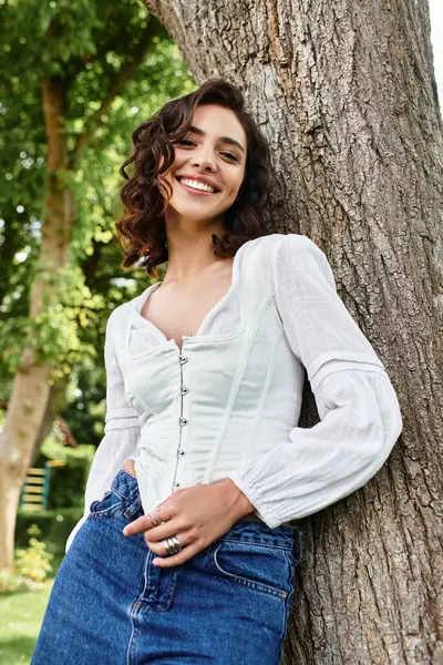 Bright summer day with a young woman smiling outdoors, enjoying the warmth in a lush park. — Stock Photo