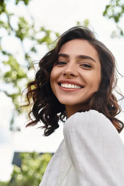 A radiant young woman with wavy brown hair enjoys the outdoors on a summer day. — Stock Photo