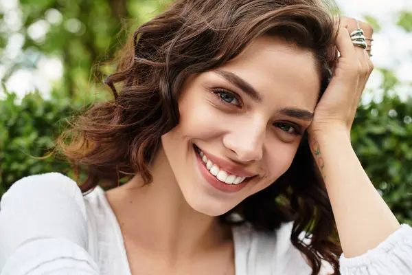 A pretty young woman enjoys a warm summer day, revealing a joyful smile while outdoors. — Stock Photo