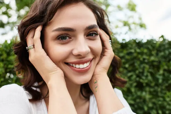A cheerful young woman with wavy brown hair is relaxing in a vibrant park, embracing the summer sun. — Stock Photo