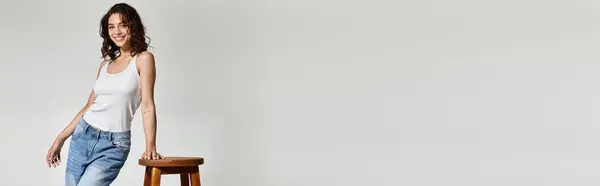 A beautiful woman with elegant makeup poses gracefully in a modern studio with a grey backdrop, banner — Stock Photo