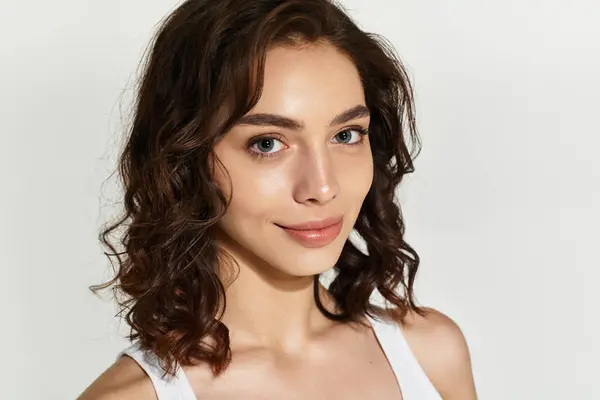 A young woman showcases her beauty with artistic makeup while posing in a studio setting. — Stock Photo