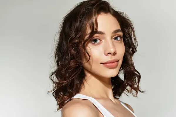 A young woman showcases her lovely makeup while posing gracefully in a modern studio. — Stock Photo