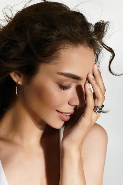 A young woman poses gracefully in a studio, highlighting her exquisite makeup and brown hair. — Stock Photo