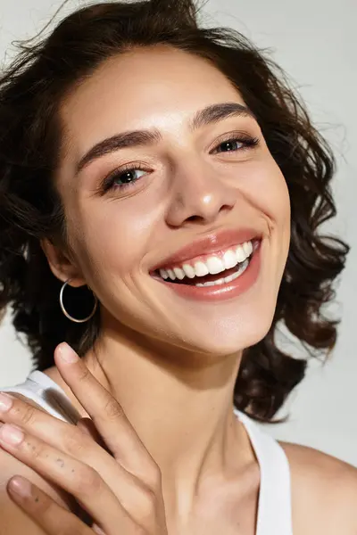 A joyful young woman with beautiful makeup and curly hair is posing in a trendy studio setting. — Stock Photo