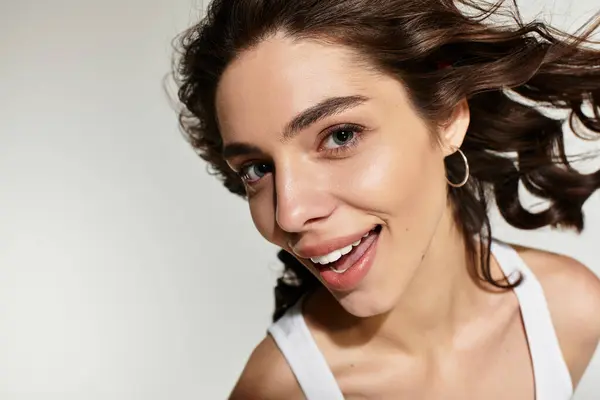 A young woman with stunning makeup poses confidently in a modern studio. Her curly hair adds charm. — Stock Photo