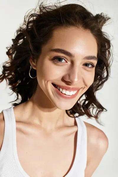 A young woman smiles brightly, showing off her stunning makeup against a grey backdrop. — Stock Photo