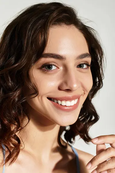 A radiant young woman with mesmerizing curls poses confidently in a studio, enhancing her beauty. — Stock Photo