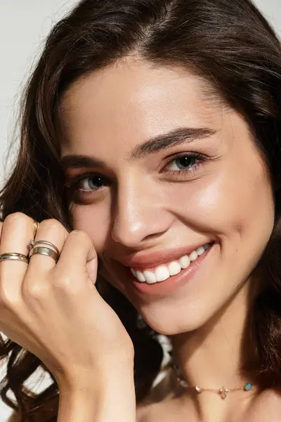 A young woman showcases her beauty with elegant makeup, radiating confidence in a studio setting. — Stock Photo