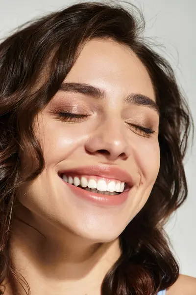 A young woman with lovely makeup beams joyfully in a studio setting, showcasing her beauty. — Stock Photo