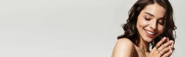 In a studio setting, a young woman expresses joy with a charming smile and elegant makeup, banner — Stock Photo