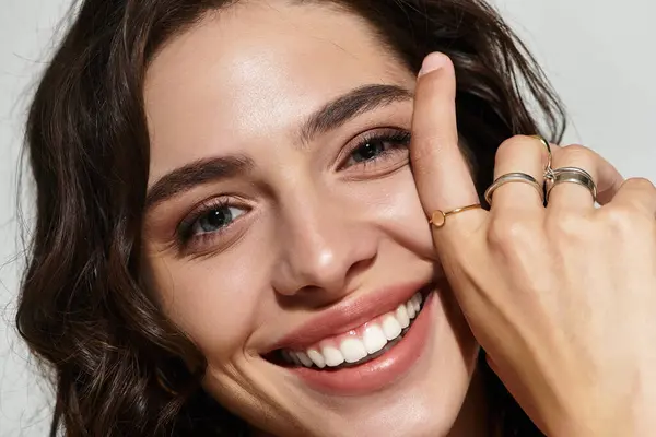 Radiant young woman poses confidently in a studio, highlighting her striking makeup and jewelry. — Stock Photo