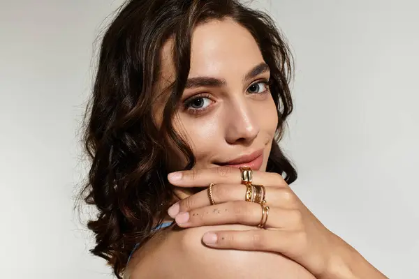 Beautiful young woman showcases her makeup and jewelry in a professional studio environment. — Stock Photo