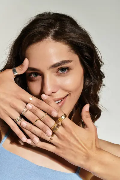 A young woman with stunning makeup poses in a grey studio, showcasing her rings and features. — Stock Photo