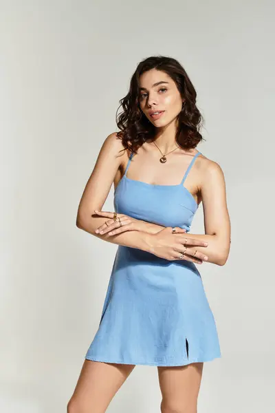 A young woman with beautiful makeup showcases her style in a blue summer dress, striking a pose. — Stock Photo