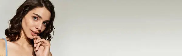 A young beautiful woman showcasing striking makeup poses elegantly against a gray backdrop, banner — Stock Photo