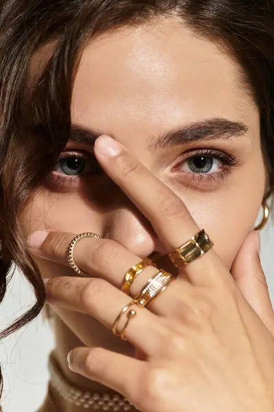 A young woman showcases her beautiful makeup and jewelry in a studio setting. — Stock Photo