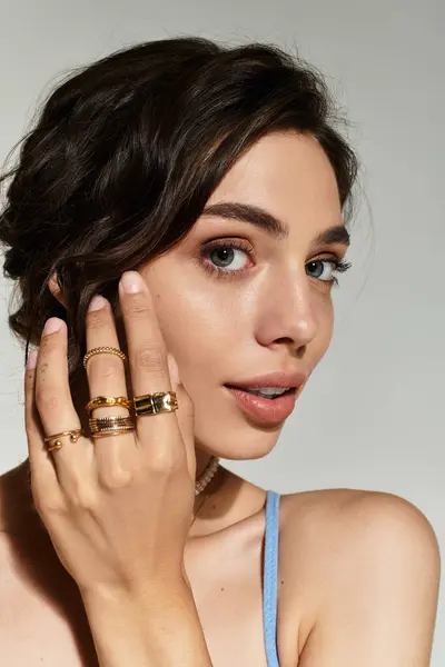 A beautiful woman poses gracefully in a studio, showcasing her stunning makeup and stylish rings. — Stock Photo