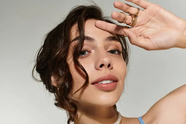 A young woman showcases her artistic makeup skills in a neutral studio environment. — Stock Photo