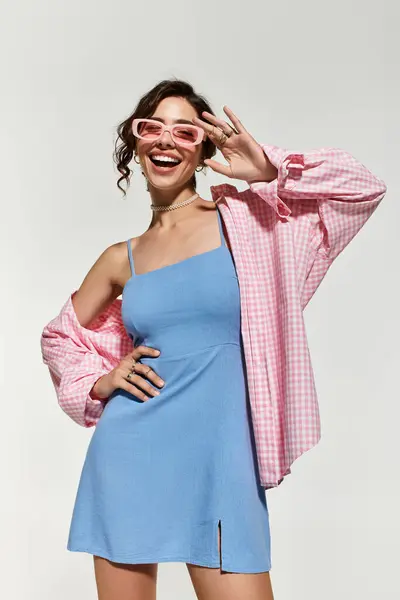 A joyful young woman in a blue summer dress with brown hair and lovely makeup poses playfully. — Stock Photo