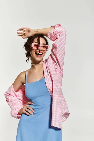 A young woman with brown hair and vibrant makeup strikes a playful pose while wearing a blue dress. — Stock Photo
