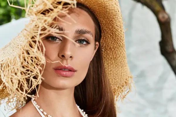 A radiant young woman enjoys summer outdoors, wearing a chic straw hat and exuding natural beauty. — Stock Photo
