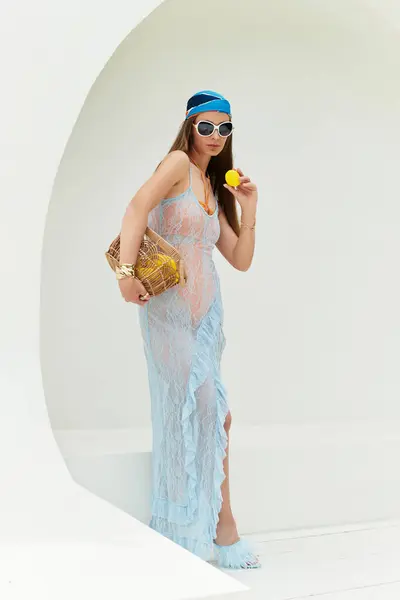 Bright sunlight highlights a stunning woman in light attire savoring a citrus treat. — стокове фото